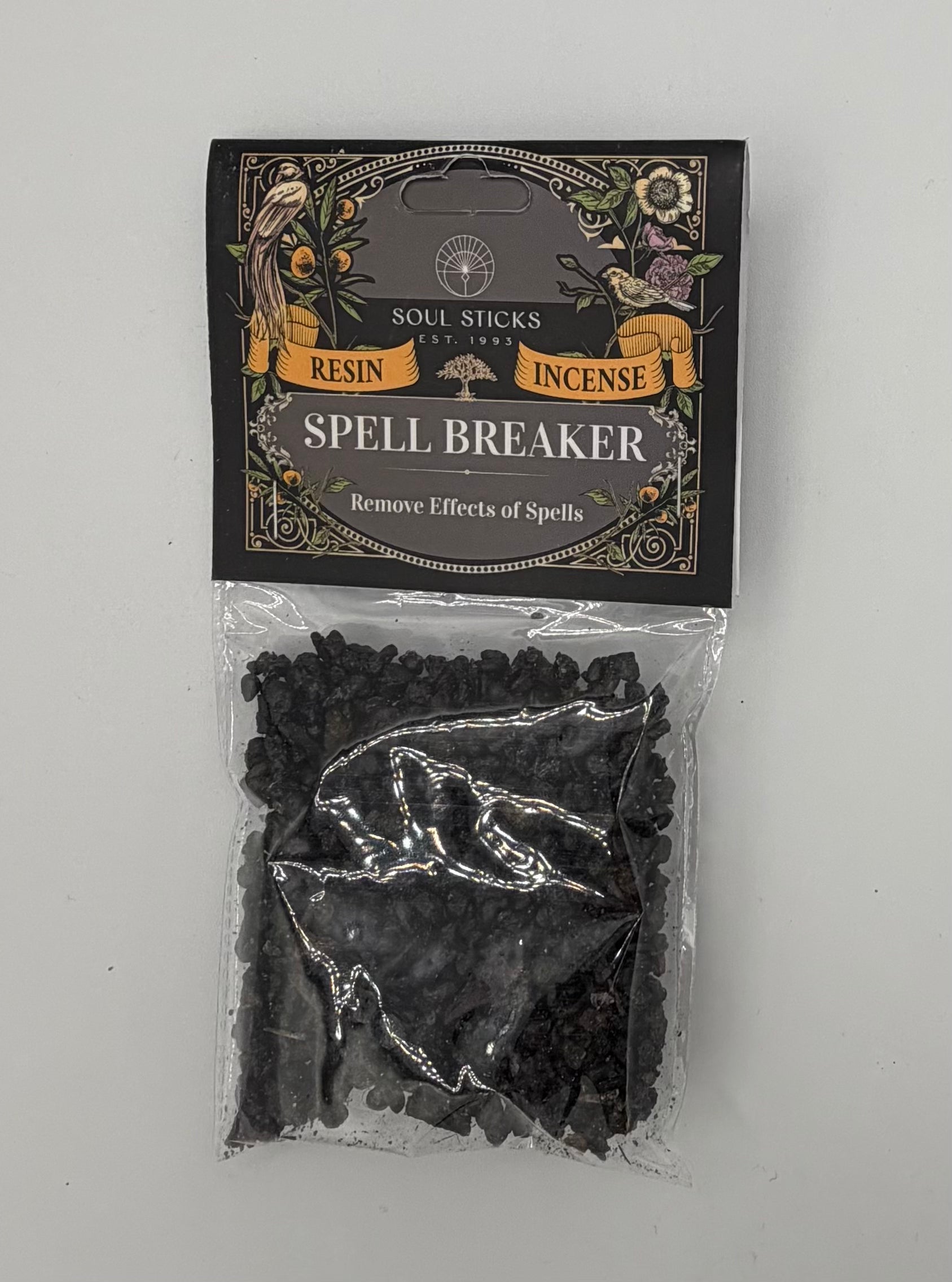 A package of Spell Breaker resin and incense soul sticks by Soul Sticks Inc., featuring a black header card with gold and white lettering and a clear plastic bag containing dark, irregularly shaped crystals below.
